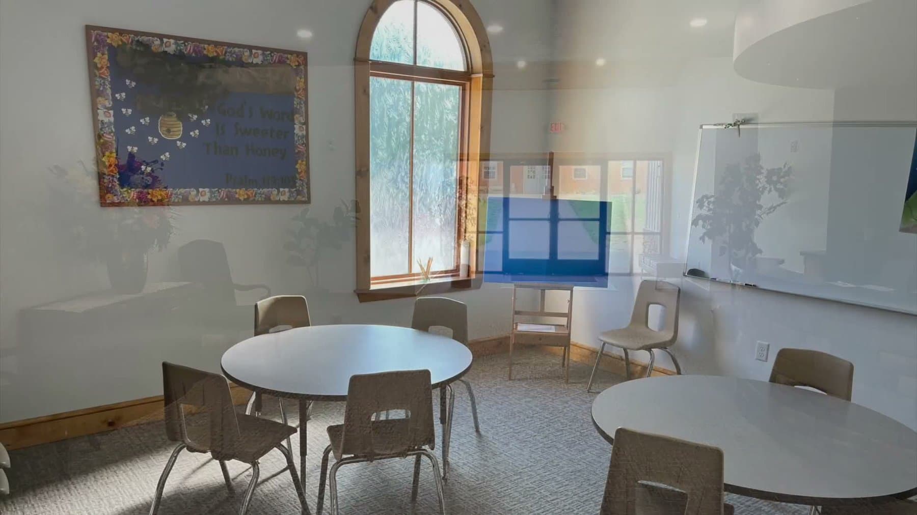 A finished classroom in the new building with a round table, chairs, a whiteboard and an arched window