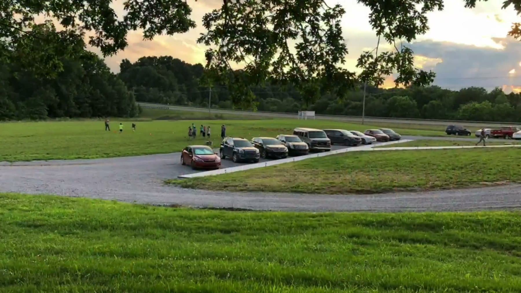 Evening light over the field and drive at 610 Myers Lane, cars parked along the gravel
