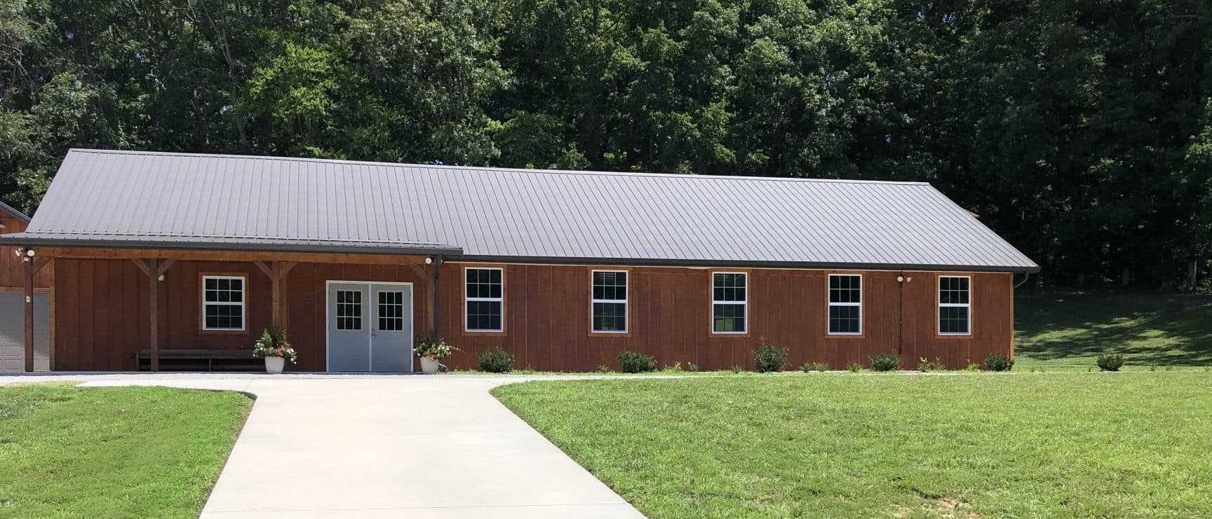 The finished Tabernacle, board-and-batten with a standing-seam roof and a covered porch